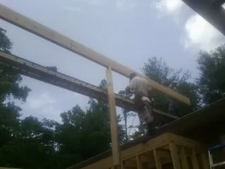 Carpenter setting a ridge beam over a new addition frame — Ice Dam Removal by Roofing Brothers in Elton