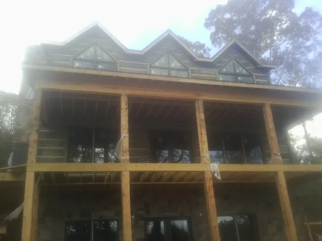 Dormers and porch framing on a large log home under construction — Roof Coating work by our crew in Elton