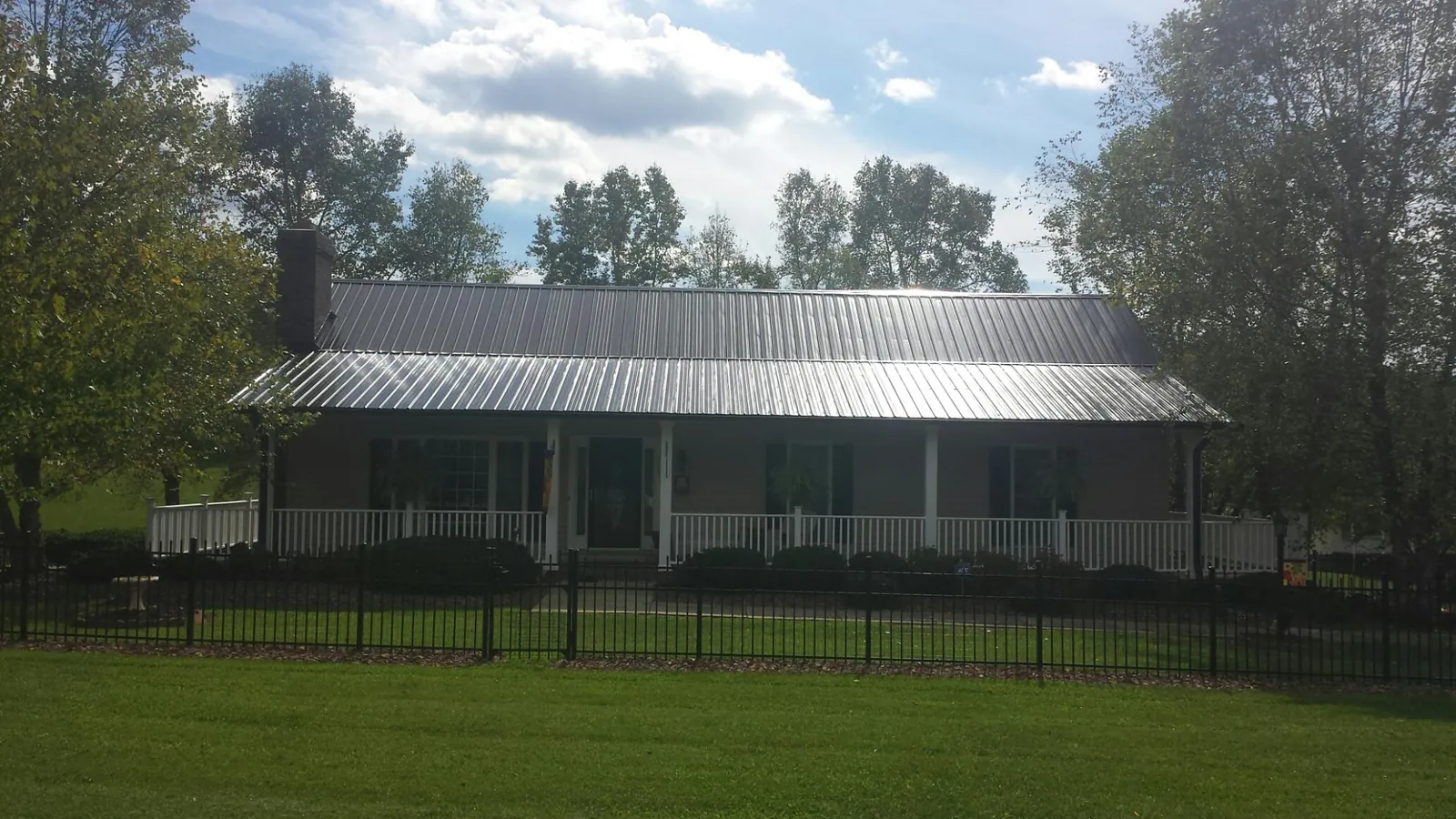 Gray metal roof on a brick ranch with a full width front porch — Gutter Guard Installation work by our crew in Elton