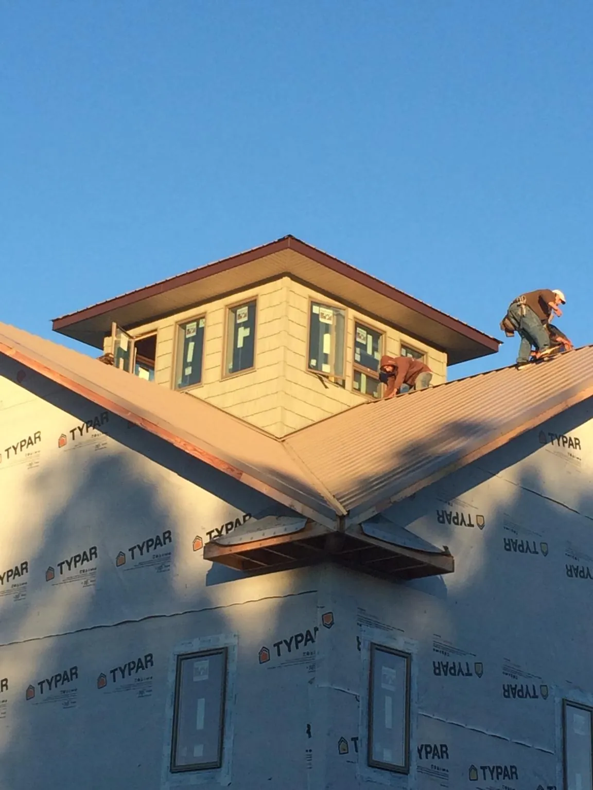 Roofers working around a rooftop cupola on a new metal roof at sunset — Roof Waterproofing in Elton by Roofing Brothers